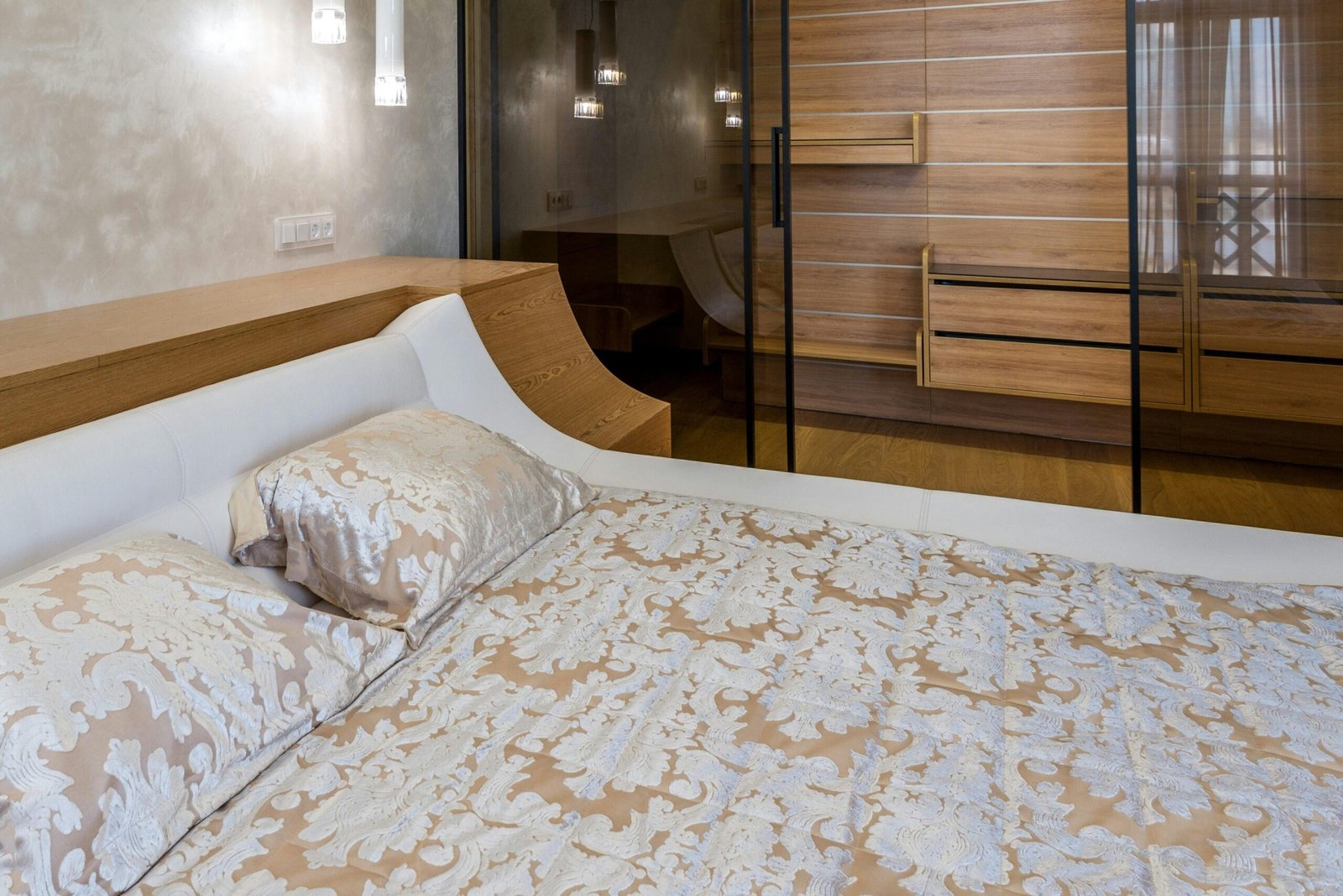 Luxury interior design of bedroom furnished with comfortable king sized bed and spacious wardrobe closet with glass doors and empty shelves